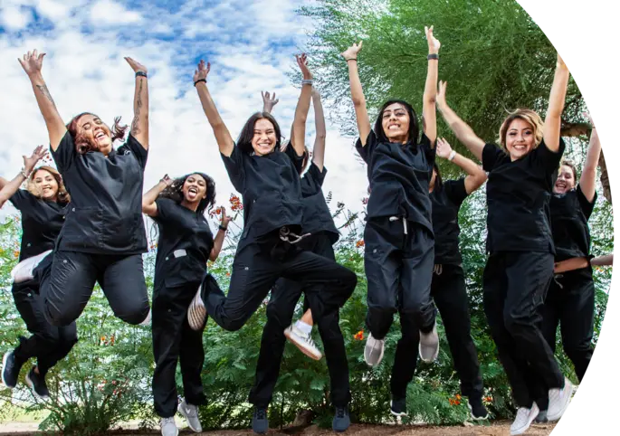 Students jumping in a pose together in their scrubs